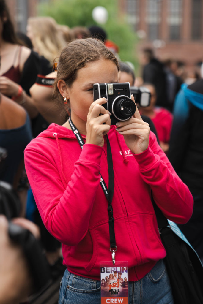 Junge Frau macht eine Aufnahme mit der Instax Sofortbildkamera